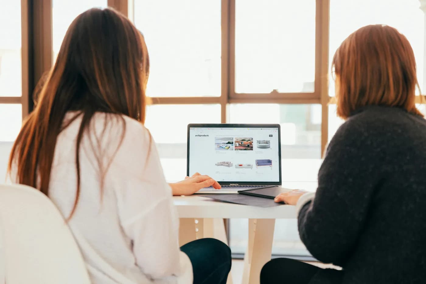 Two people sitting together at a table, looking at a laptop screen